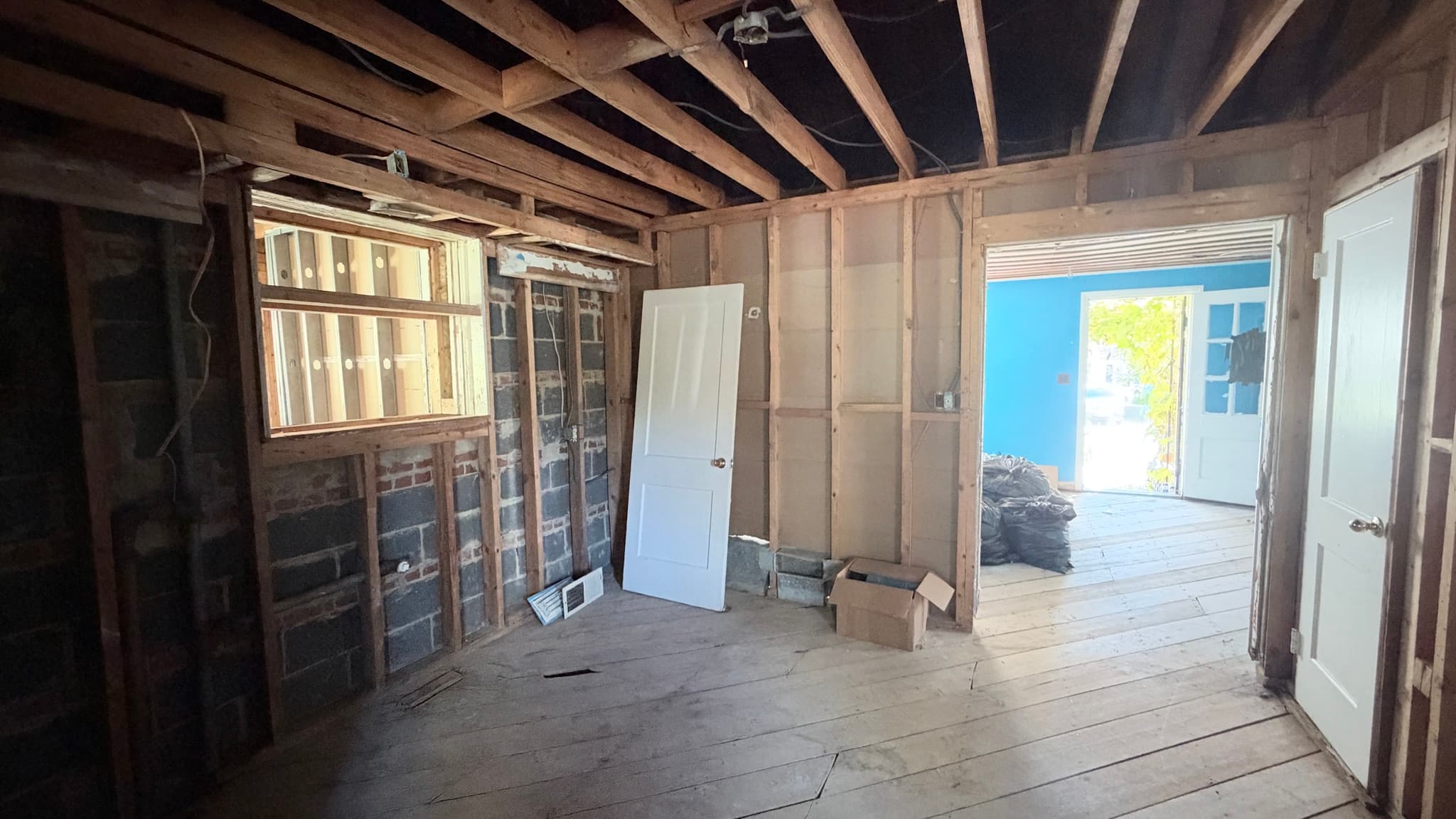 Main-level room open to the studs and block, looking toward the front room