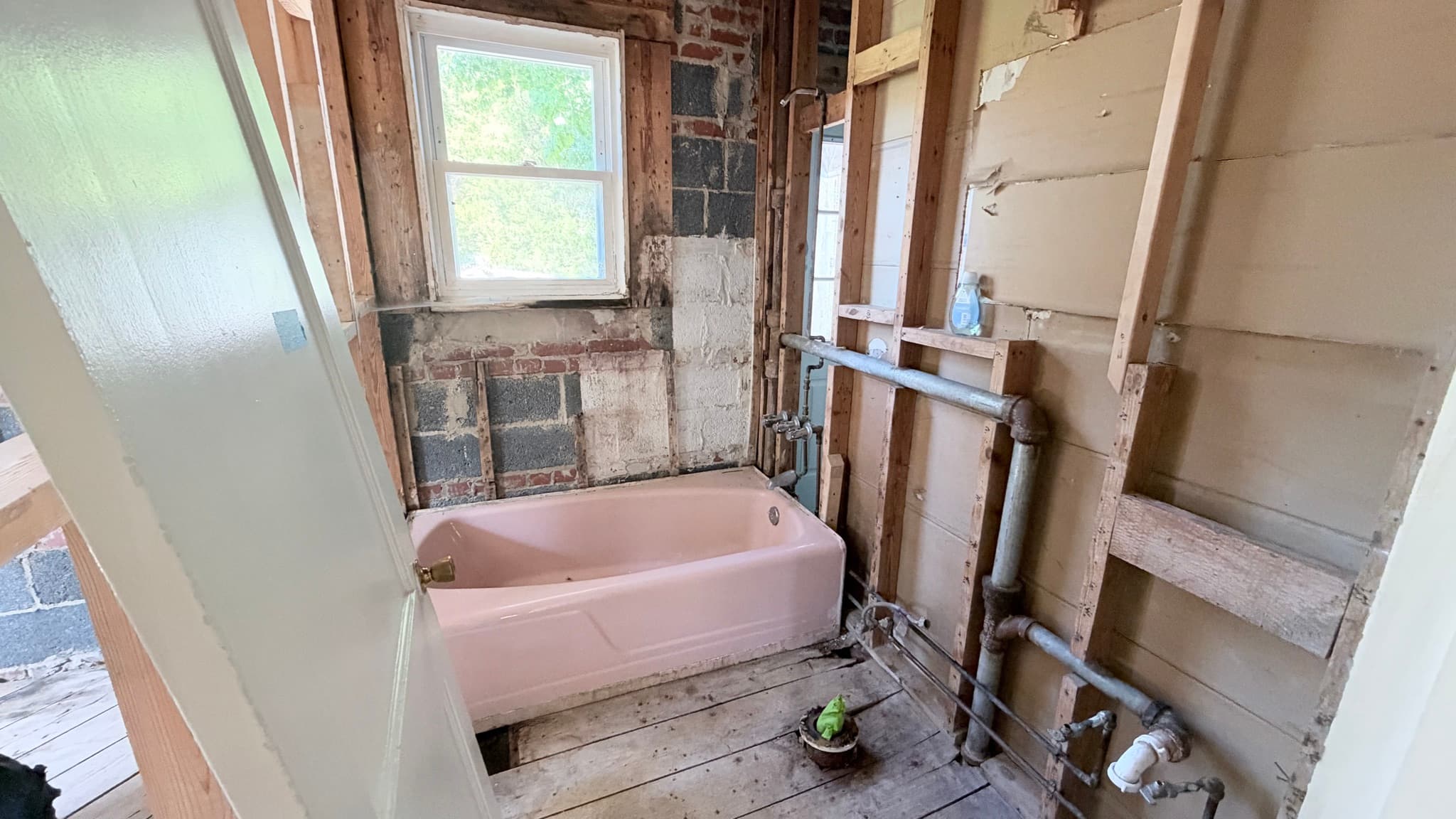 Bathroom opened to the studs and block, plumbing exposed, original tub still in place