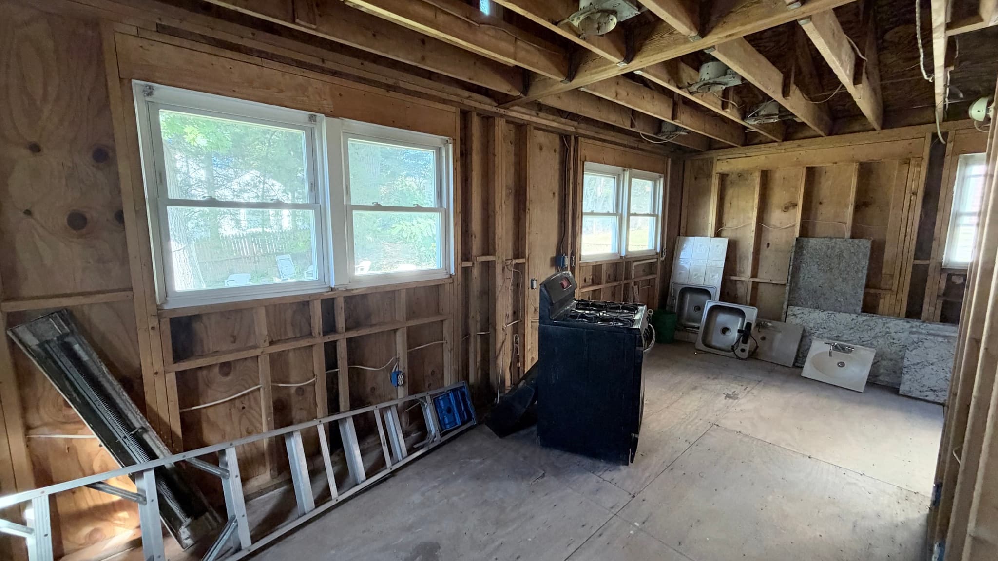 Kitchen addition open to the framing — old range and countertop pieces still on site