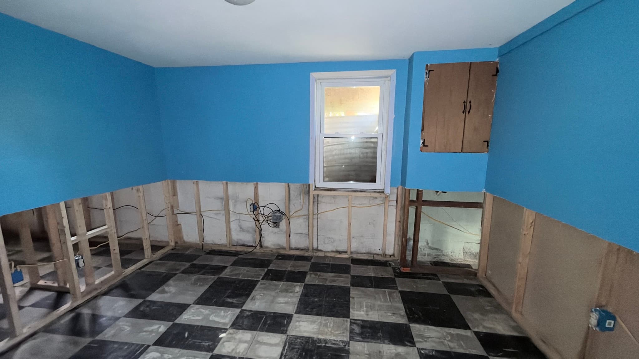 Lower-level room with window, lower section of drywall removed